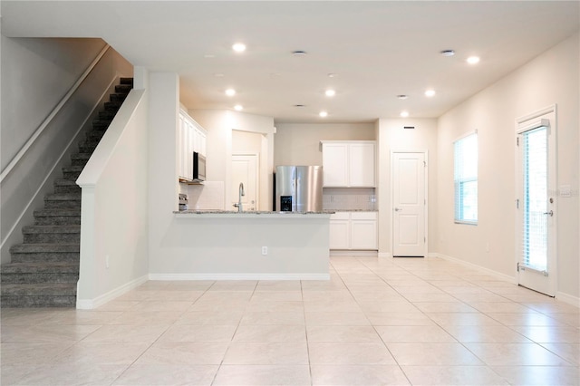 kitchen featuring white cabinets, light stone counters, a wealth of natural light, and appliances with stainless steel finishes