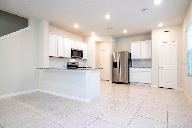 kitchen with light stone countertops, white cabinets, kitchen peninsula, and appliances with stainless steel finishes