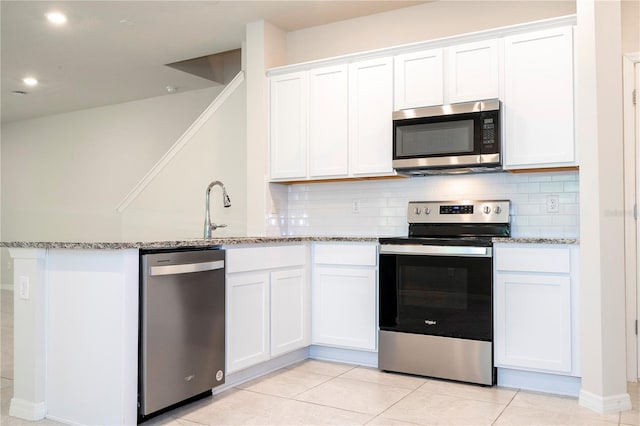 kitchen featuring light stone countertops, stainless steel appliances, light tile patterned floors, and white cabinetry