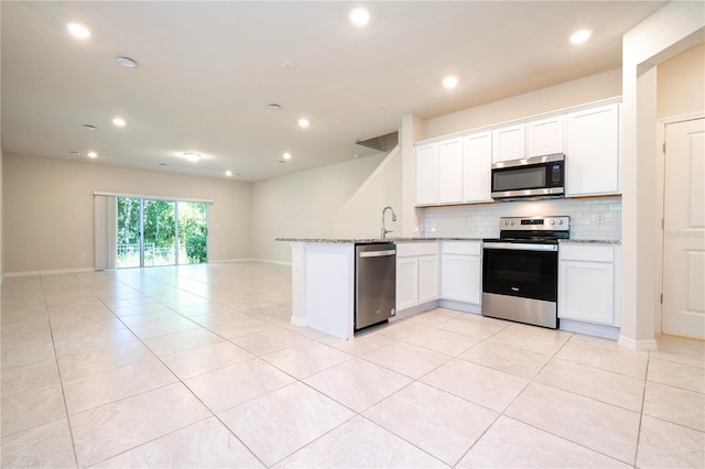 kitchen with white cabinets, light tile patterned floors, appliances with stainless steel finishes, light stone countertops, and decorative backsplash