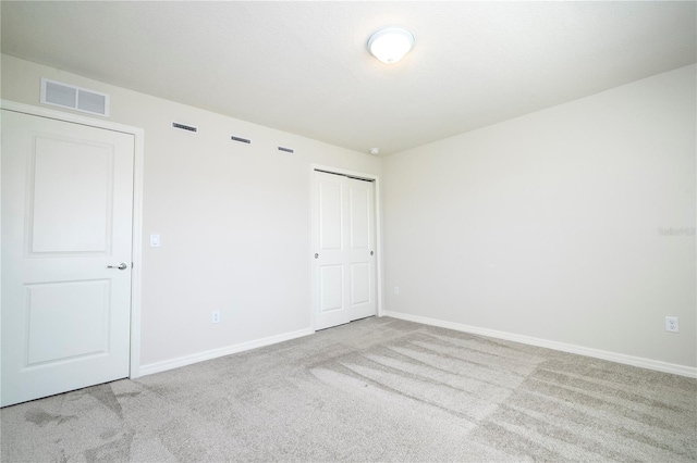 unfurnished bedroom with light colored carpet and a closet