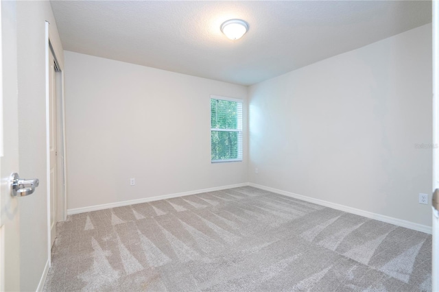 spare room with light carpet and a textured ceiling