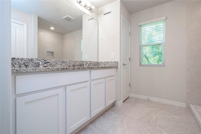 bathroom with vanity, tile patterned flooring, and a tile shower