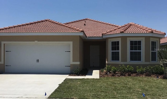 mediterranean / spanish house featuring a garage and a front yard