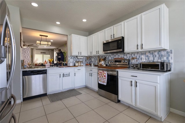 kitchen featuring stainless steel appliances, white cabinets, decorative backsplash, a textured ceiling, and light tile patterned floors