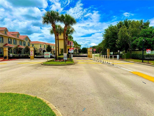 view of road with traffic signs, a residential view, and a gated entry