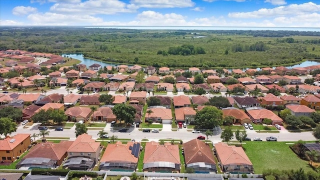 drone / aerial view with a residential view, a view of trees, and a water view