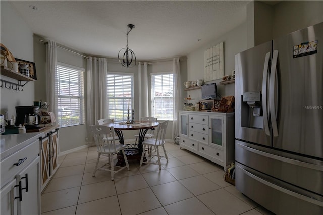 dining area with light tile patterned flooring, baseboards, and a textured ceiling