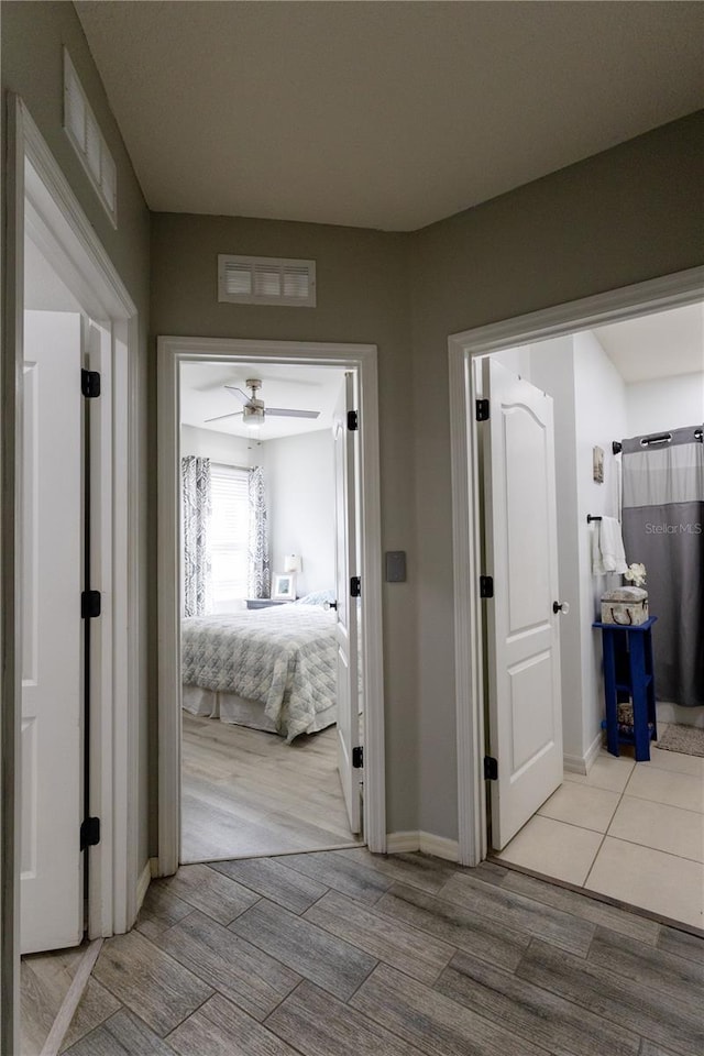 hallway featuring visible vents, baseboards, and wood finished floors