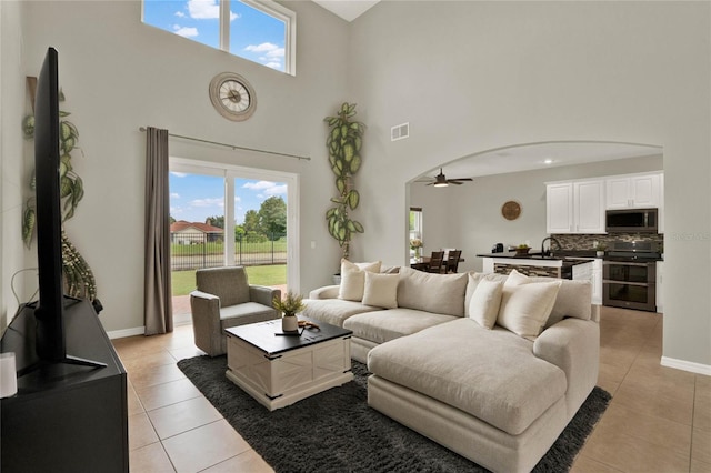 tiled living room with a high ceiling, ceiling fan, and sink