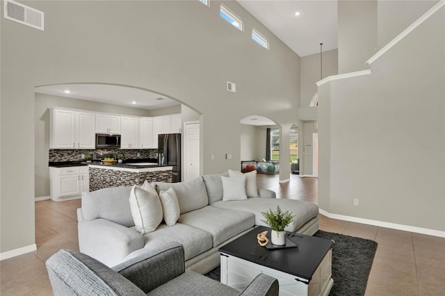 living area with arched walkways, visible vents, plenty of natural light, and light tile patterned floors