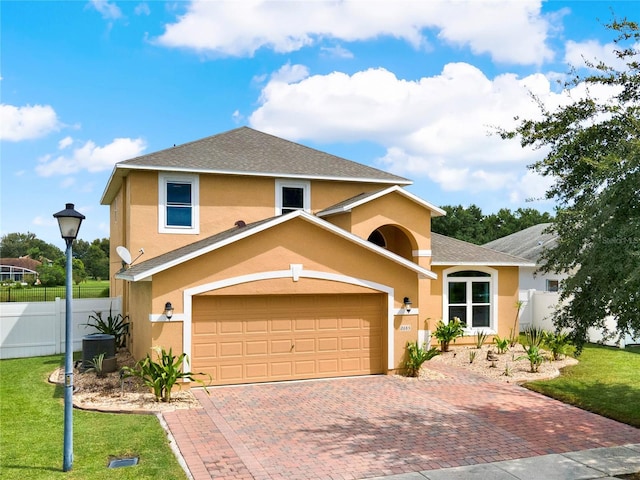 view of front of property with decorative driveway, a front yard, fence, and stucco siding