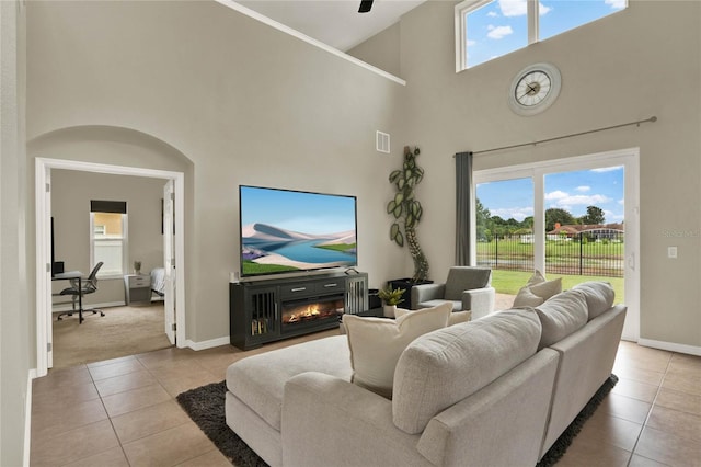 living area with a glass covered fireplace, visible vents, baseboards, and light tile patterned floors