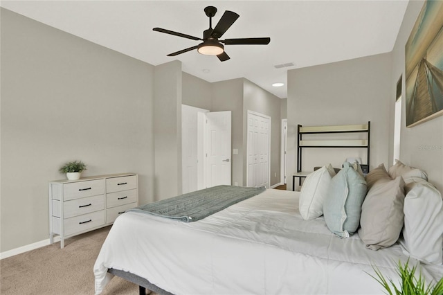 bedroom with a closet, light colored carpet, visible vents, ceiling fan, and baseboards