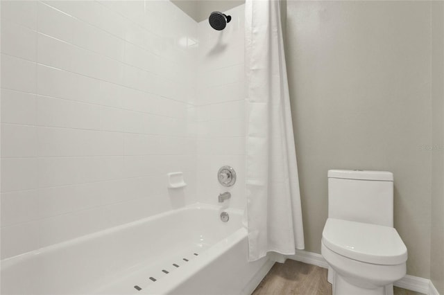 full bathroom featuring shower / bath combo, baseboards, toilet, and wood finished floors