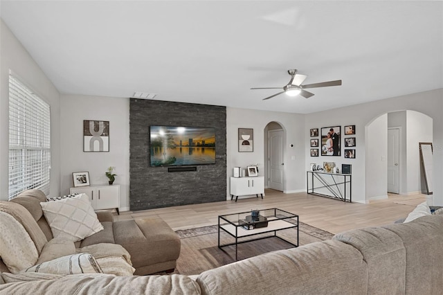 living room featuring light hardwood / wood-style floors, ceiling fan, and a fireplace