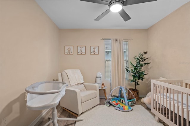 bedroom featuring ceiling fan and a nursery area