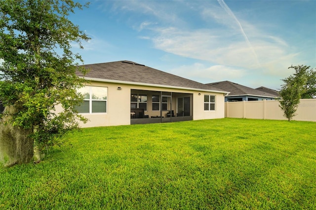 rear view of house featuring a lawn and a sunroom