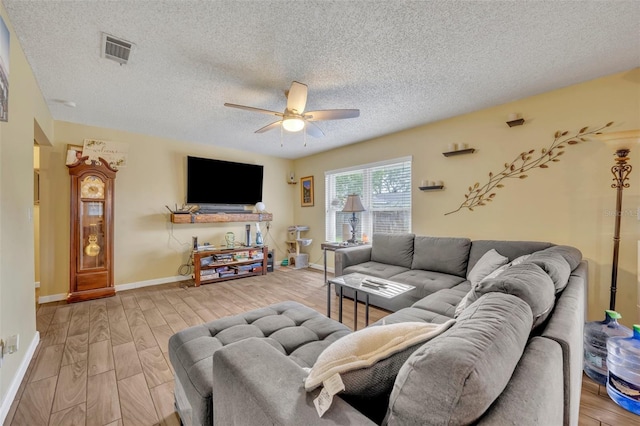 living room with light hardwood / wood-style flooring, a textured ceiling, and ceiling fan