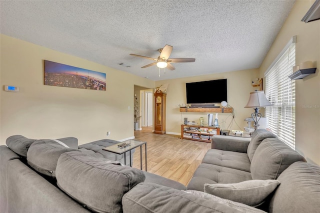 living room with ceiling fan, wood-type flooring, and a textured ceiling