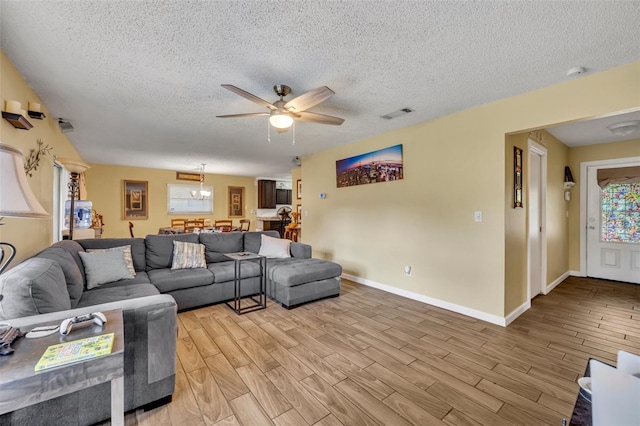 living room with light hardwood / wood-style floors, a textured ceiling, and ceiling fan