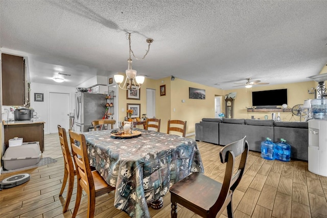 dining space featuring a textured ceiling, ceiling fan with notable chandelier, and light hardwood / wood-style floors