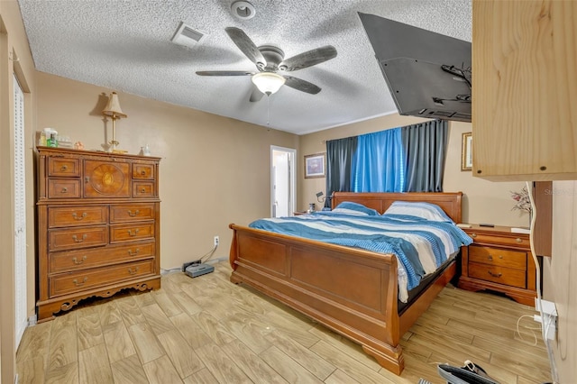 bedroom featuring a textured ceiling, light wood-type flooring, and ceiling fan