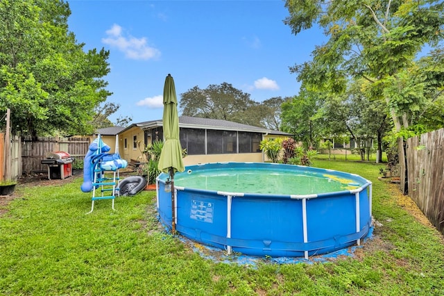 view of swimming pool with grilling area, a sunroom, and a lawn