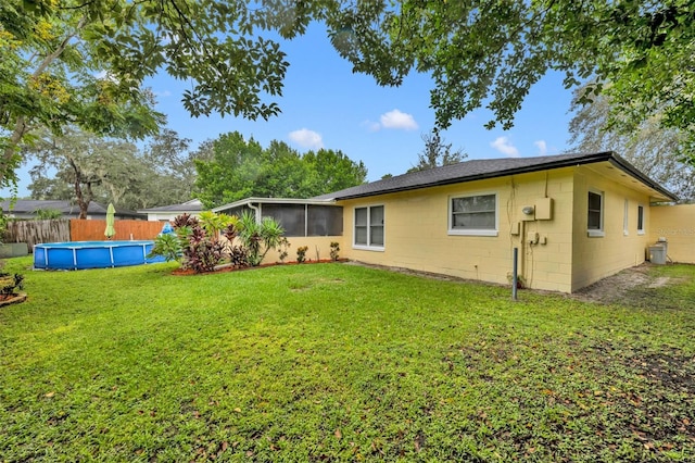 back of property featuring a fenced in pool, a sunroom, and a lawn