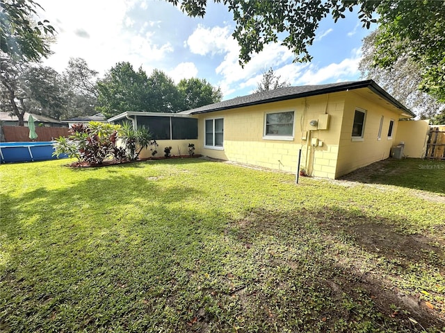 rear view of property with a sunroom and a yard