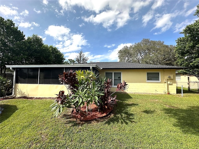 rear view of house featuring a sunroom and a lawn