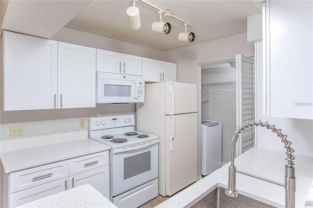 kitchen featuring a textured ceiling, washer and clothes dryer, white appliances, and white cabinetry