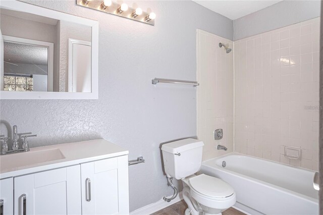 full bathroom with tiled shower / bath, vanity, and toilet