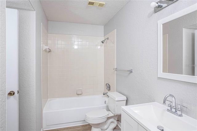 full bathroom featuring vanity, tiled shower / bath, a textured ceiling, and toilet