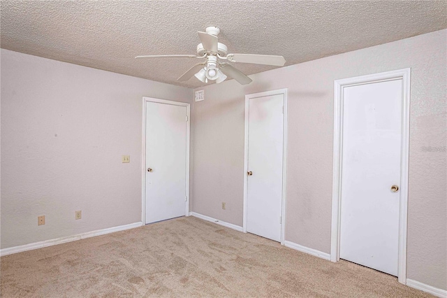 unfurnished bedroom with light carpet, a textured ceiling, and ceiling fan