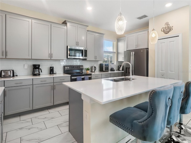 8938 Cabot Cliffs Dr, Davenport, FL 33896 - kitchen featuring stainless steel appliances, gray cabinets, a sink, light marble finish flooring, and a kitchen bar