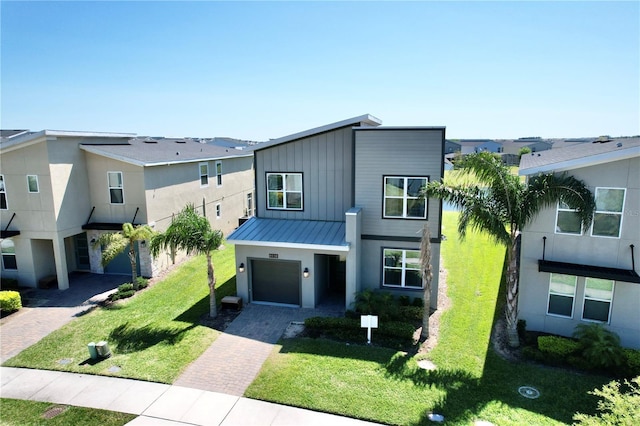 8938 Cabot Cliffs Dr, Davenport, FL 33896 - contemporary home with decorative driveway, a garage, a standing seam roof, a front yard, and metal roof