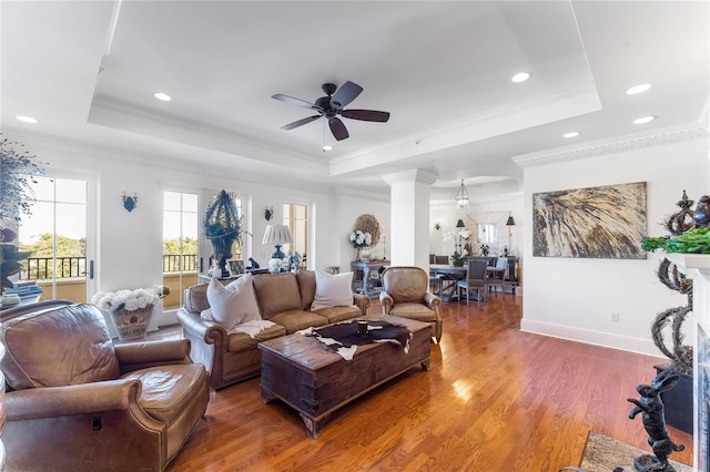 living room with ceiling fan, hardwood / wood-style flooring, a tray ceiling, and crown molding