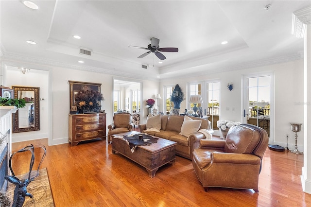 living room featuring a tray ceiling, ceiling fan, hardwood / wood-style floors, and crown molding