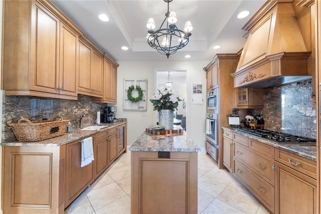 kitchen featuring custom range hood, decorative backsplash, a tray ceiling, a center island, and a notable chandelier