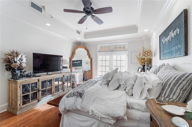 bedroom with ornamental molding, ceiling fan, a raised ceiling, and hardwood / wood-style flooring