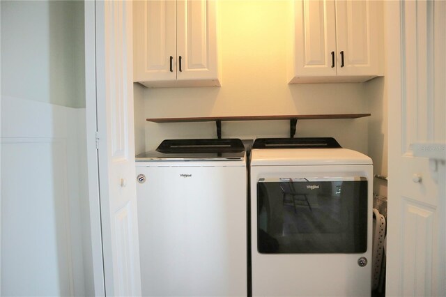 clothes washing area featuring cabinets and washing machine and clothes dryer