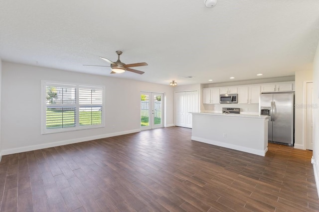 kitchen with stainless steel appliances, ceiling fan, dark wood-type flooring, a center island, and white cabinetry