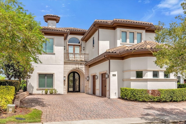 mediterranean / spanish house with a balcony and french doors