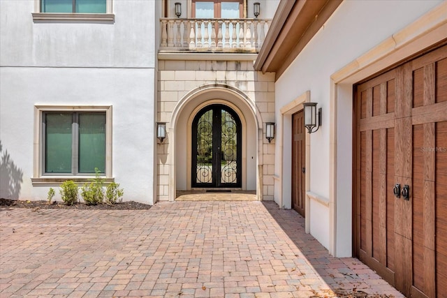 view of exterior entry featuring french doors and a balcony