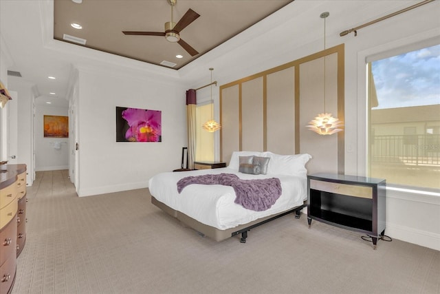 carpeted bedroom with ceiling fan, a tray ceiling, and crown molding