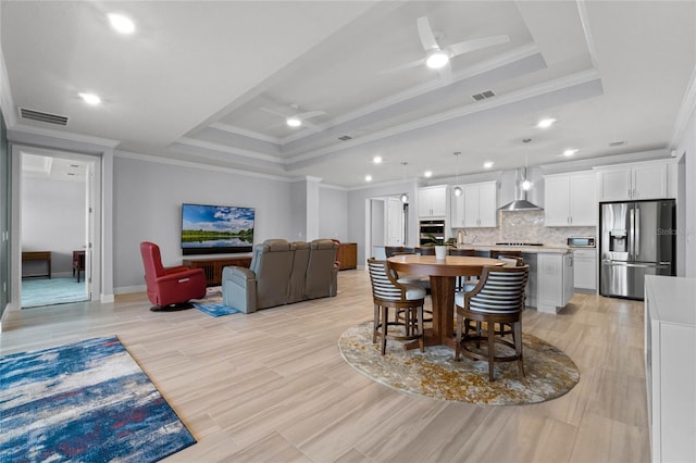 dining area featuring light hardwood / wood-style floors, ceiling fan, a raised ceiling, and crown molding