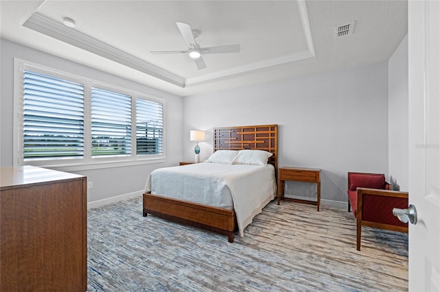 bedroom featuring a raised ceiling, ornamental molding, ceiling fan, and light hardwood / wood-style flooring