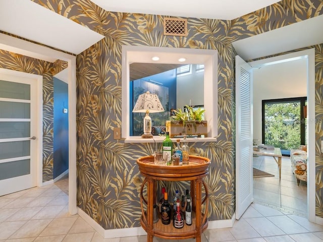 hallway featuring baseboards, tile patterned floors, visible vents, and wallpapered walls