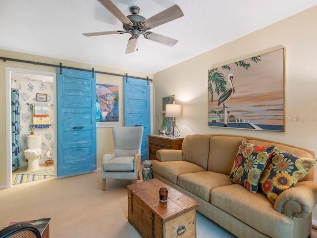 carpeted living room featuring a barn door and a ceiling fan